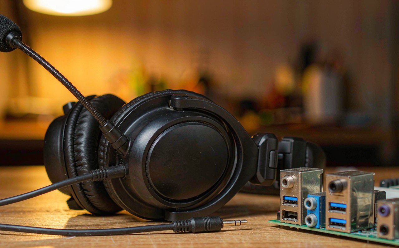 A gaming headset with a boom microphone resting on a desk beside an audio jack splitter cable