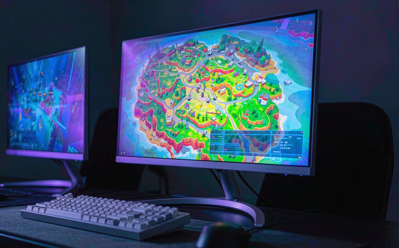A PC gaming setup with colorful purple and blue lighting, showing a fast-paced battle royale style game on screen