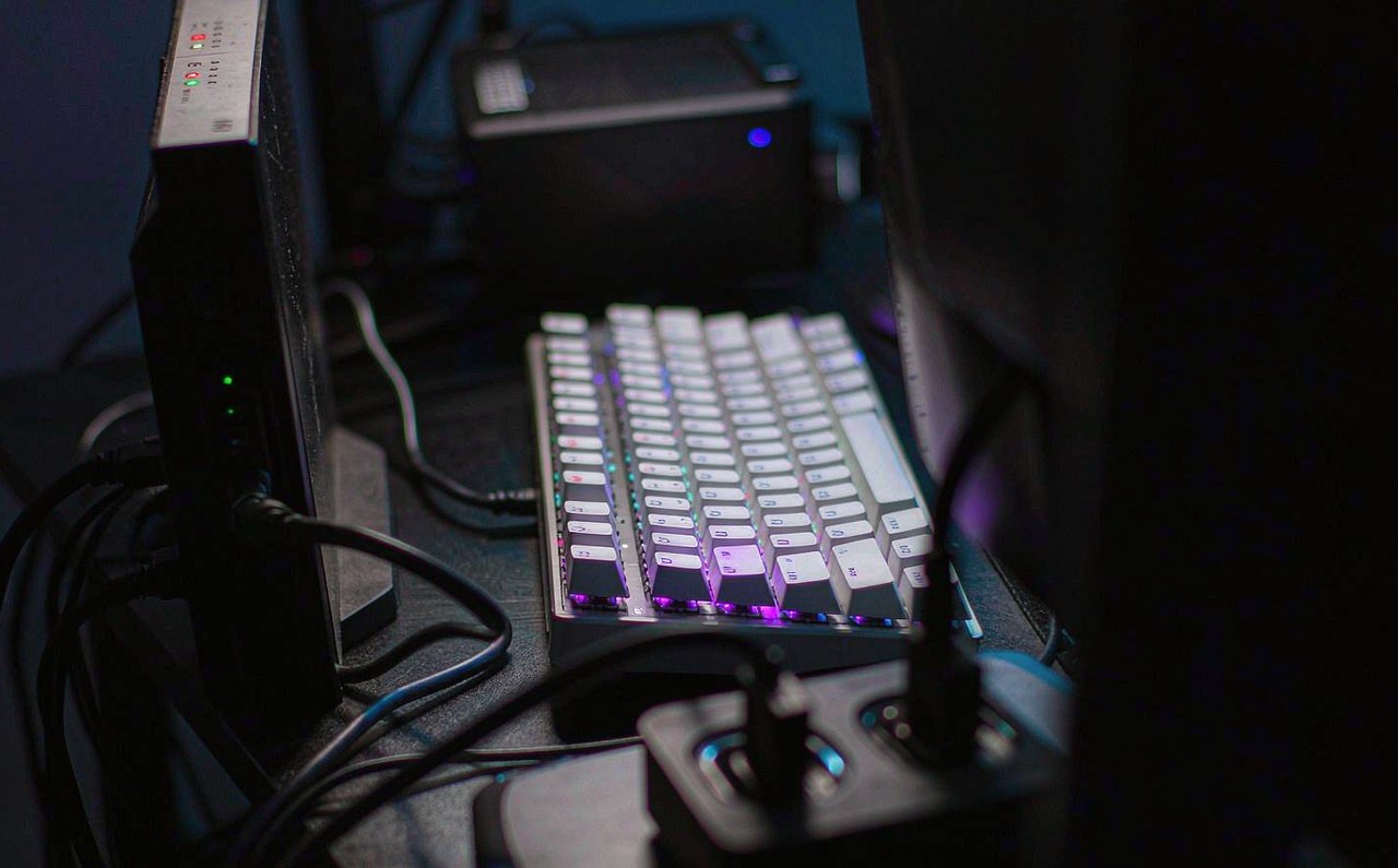 A gaming desk at night with an ethernet cable plugged into a router with glowing LEDs